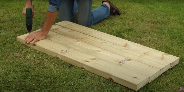 Charles is drilling some holes in the wood pieces