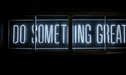 A neon sign displaying “Do Something Great”