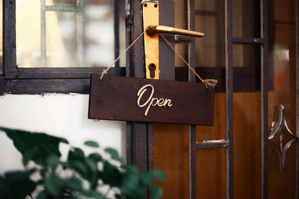 An “open” sign hanging on a wood door