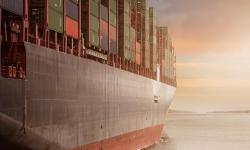 A container ship going towards the sunrise.