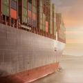 A container ship going towards the sunrise.