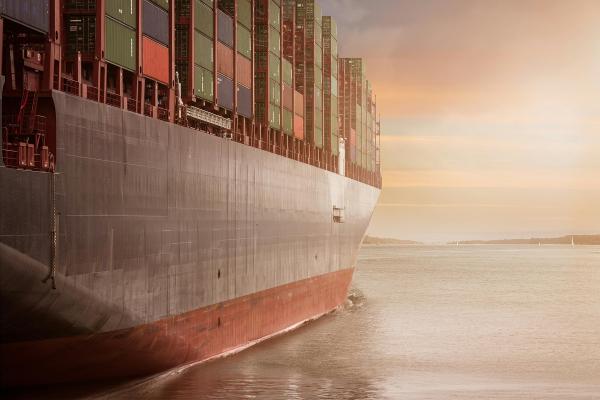 A container ship going towards the sunrise.