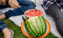 A man and a woman scooping into a watermelon