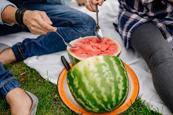 A man and a woman scooping into a watermelon