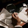 A man with a magnifying glass deciphering symbols