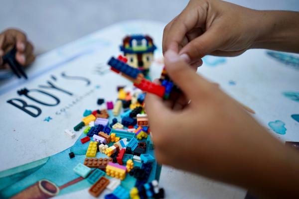 Children’s hands play with colorful toy blocks on a table inside a room in East Java, Indonesia.