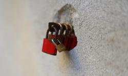 A series of red padlocks attached to a stone wall